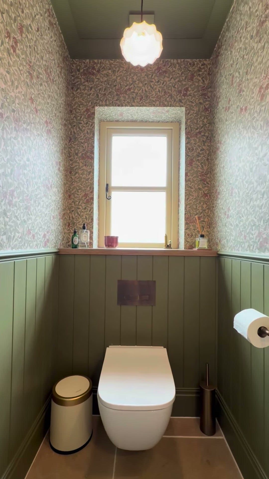 Cloakroom with floral wallpaper, green tongue-and-groove panelling and aged bronze