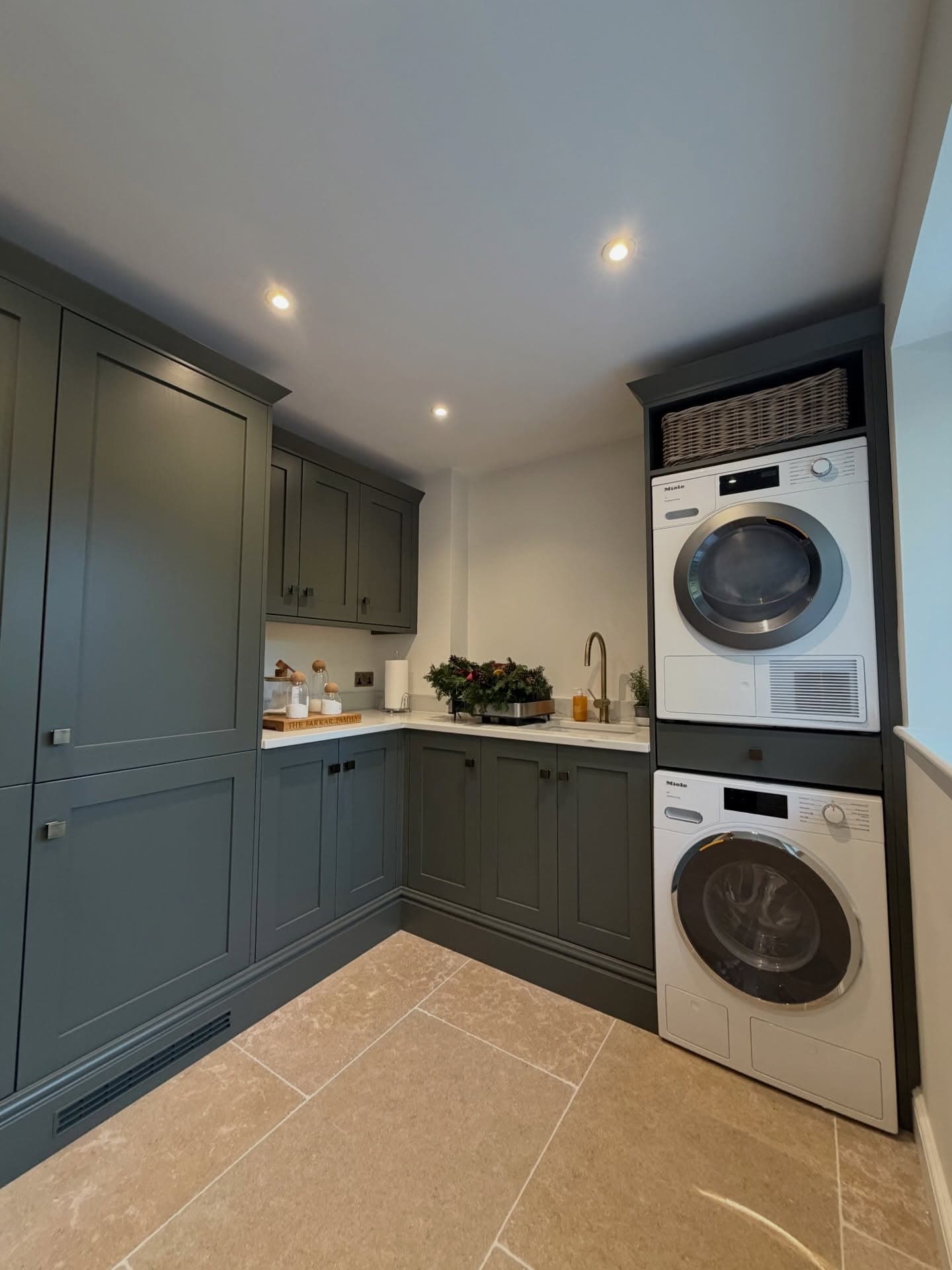 Utility room with stacked washer and dryer in green in-frame cabinetry