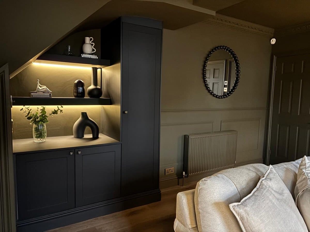 Renovated lounge with dark panelled walls, lit shelving and oak flooring